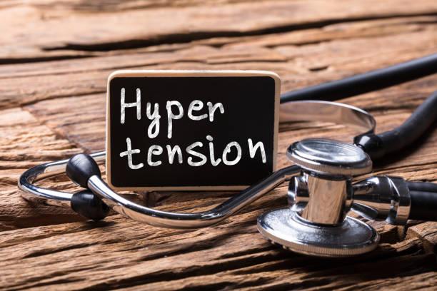 Close-up Of Stethoscope With Slate Showing Hypertension Text On Wooden Desk